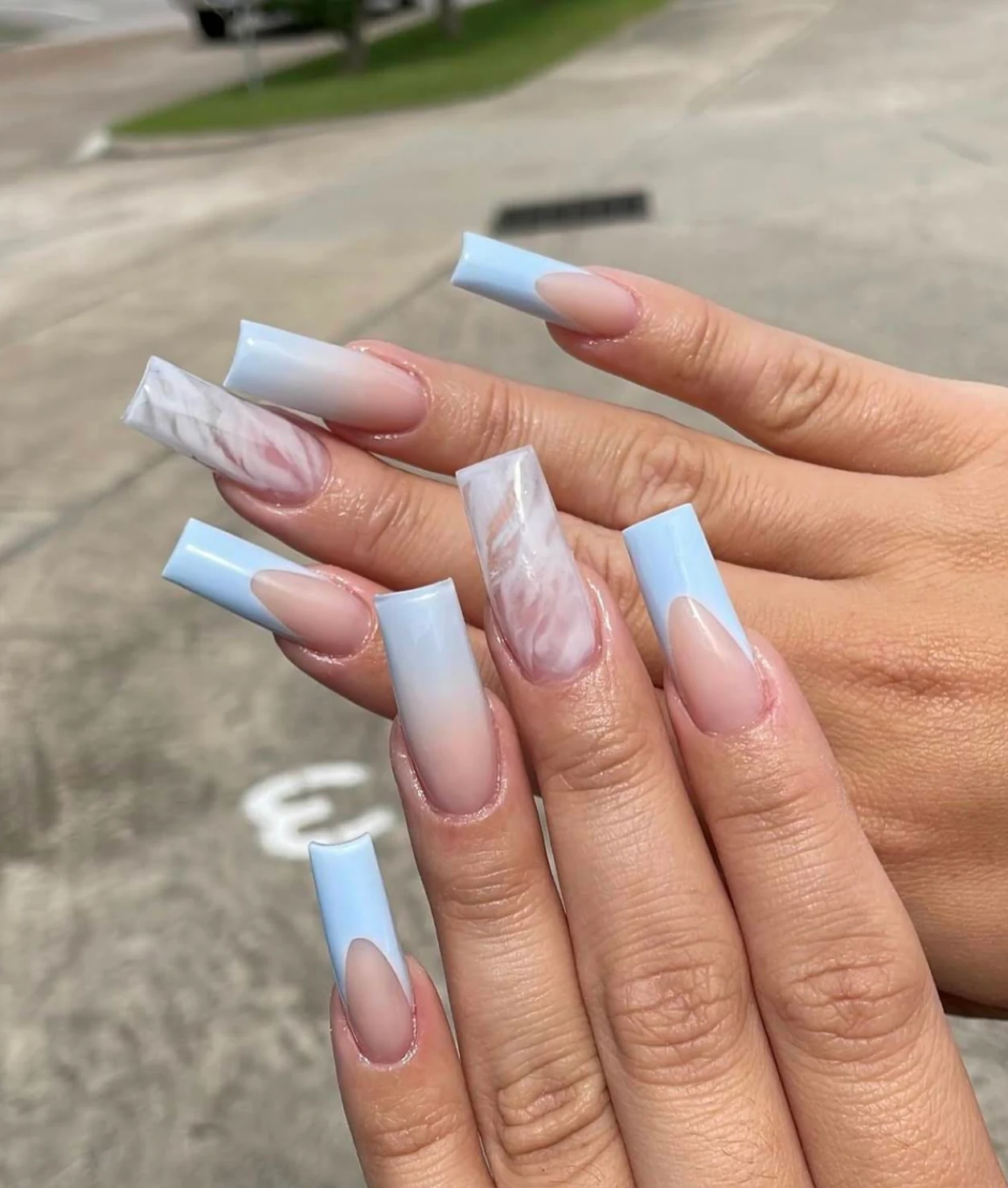 Long pale blue French-tip nails with pink and white marble accents