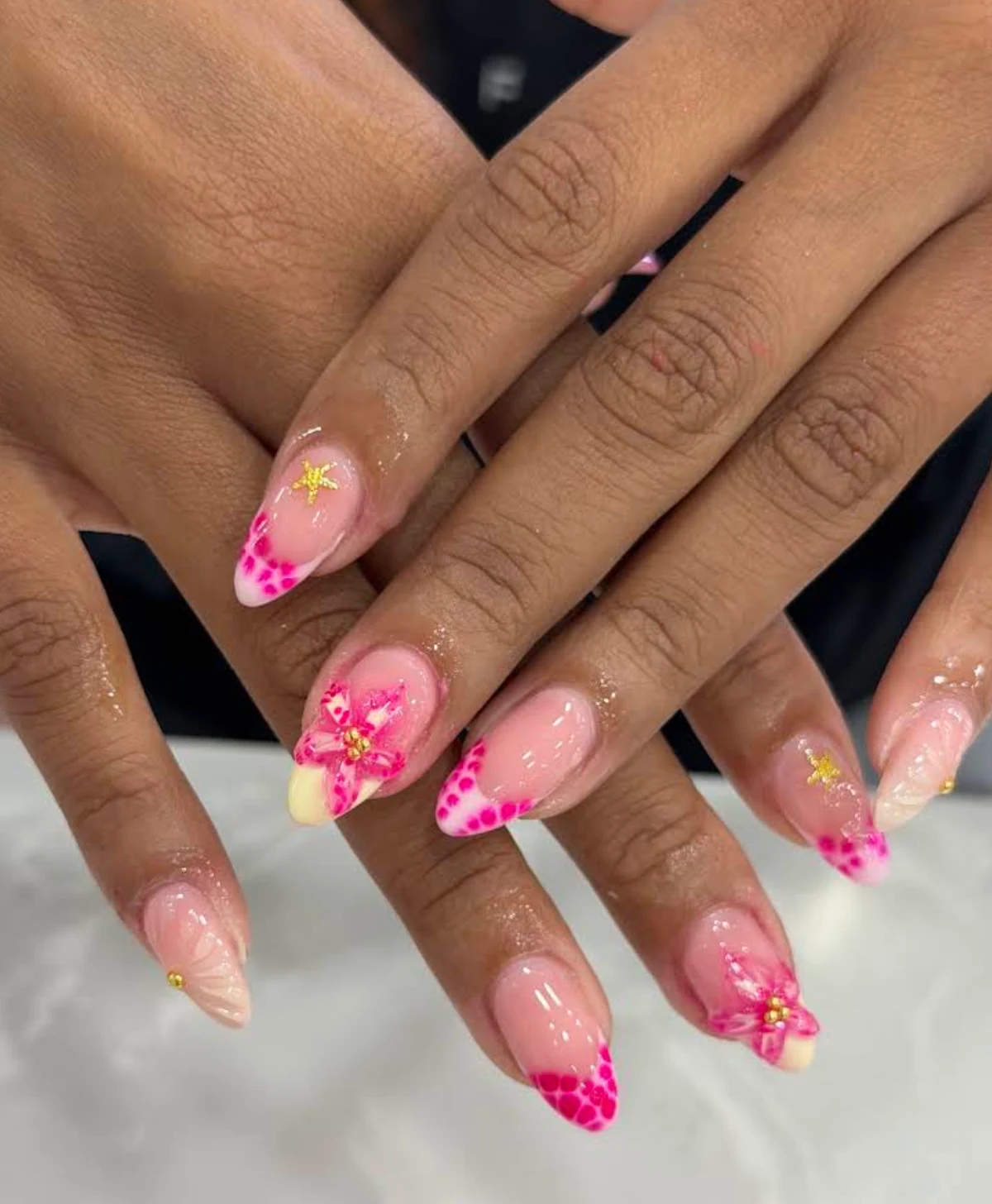 Pink floral French-tip nails with small gold star accents