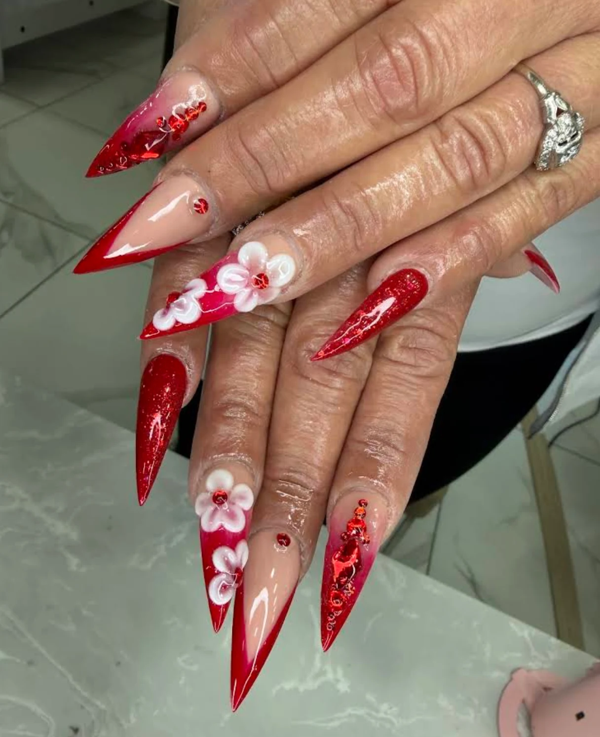 Long red and nude nails with raised white flowers and red accents